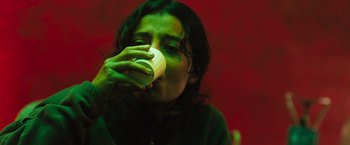 Movie still from “In the Earth” (2021), directed by Ben Wheatley – A woman drinking a cup of coffee in a dark room; Close Up shot, Low angle
