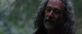 Movie still from “In the Earth” (2021), directed by Ben Wheatley – A person with long hair and a beard; Close Up shot, Low angle
