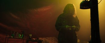 Movie still from “In the Earth” (2021), directed by Ben Wheatley – A person standing in a room with a microphone; Medium shot, Low angle