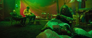 Movie still from “In the Earth” (2021), directed by Ben Wheatley – Two people sitting in a tent in the dark; Medium shot, Low angle