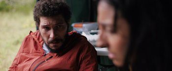 Movie still from “In the Earth” (2021), directed by Ben Wheatley – A man in a red jacket sitting next to another man; Close Up shot, Over the shoulder angle