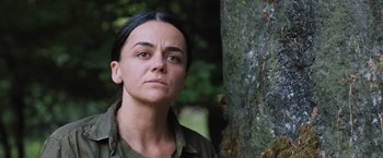 Movie still from “In the Earth” (2021), directed by Ben Wheatley – A woman standing in front of a tree looking into the distance; Close Up shot, Over the shoulder angle