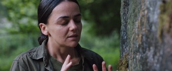 Movie still from “In the Earth” (2021), directed by Ben Wheatley – A woman is praying in the woods near a tree; Close Up shot, Over the shoulder angle
