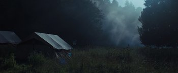 Movie still from “In the Earth” (2021), directed by Ben Wheatley – A tent in the middle of a field in the woods; Extreme Wide shot, Low angle