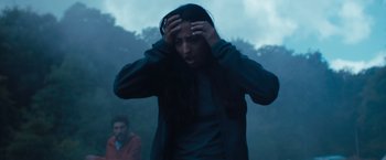 Movie still from “In the Earth” (2021), directed by Ben Wheatley – A woman holding her hands to her head in the rain; Medium shot, Low angle