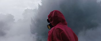 Movie still from “In the Earth” (2021), directed by Ben Wheatley – A person wearing a gas mask and a red raincoat; Close Up shot, Low angle