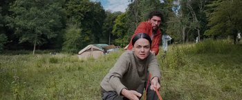 Movie still from “In the Earth” (2021), directed by Ben Wheatley – A man and a woman in a field with a rope; Medium shot, High angle