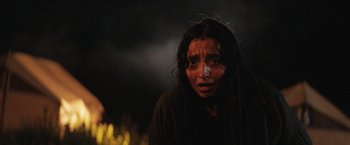 Movie still from “In the Earth” (2021), directed by Ben Wheatley – A young woman with long black hair wearing a black shirt; Close Up shot, Low angle