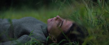 Movie still from “In the Earth” (2021), directed by Ben Wheatley – A man laying in the grass with his eyes closed; Close Up shot, Overhead angle