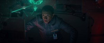 Movie still from “Independence Day: Resurgence” (2016), directed by Roland Emmerich – A man in a room with lights on the wall; Medium shot, Over the shoulder angle