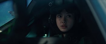 Movie still from “Independence Day: Resurgence” (2016), directed by Roland Emmerich – A woman in a helmet sitting in a car; Close Up shot, Over the shoulder angle