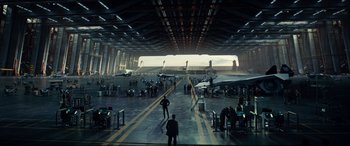 Movie still from “Independence Day: Resurgence” (2016), directed by Roland Emmerich – People are standing in an airplane hangar with airplanes; Extreme Wide shot, High angle