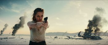 Movie still from “Independence Day: Resurgence” (2016), directed by Roland Emmerich – A woman is holding a gun in the desert; Medium shot, Low angle