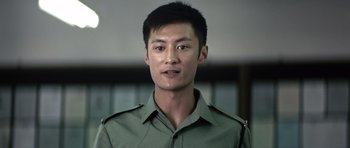 Movie still from “Infernal Affairs” (2002), directed by Alan Mak – A man in a green shirt is looking straight ahead; Close Up shot, Low angle