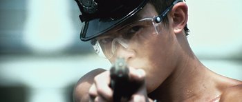 Movie still from “Infernal Affairs” (2002), directed by Alan Mak – A man in a police uniform holding a gun; Close Up shot, Low angle