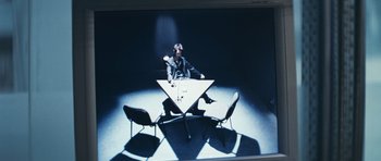 Movie still from “Infernal Affairs” (2002), directed by Alan Mak – A man sitting at a table in front of two chairs; Wide shot, High angle