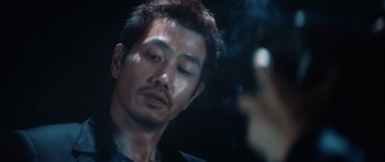 Movie still from “Infernal Affairs” (2002), directed by Alan Mak – A person smoking a cigarette in front of a mirror; Close Up shot, Over the shoulder angle