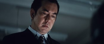 Movie still from “Infernal Affairs” (2002), directed by Alan Mak – A person wearing a suit and tie; Close Up shot, Low angle
