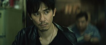 Movie still from “Infernal Affairs” (2002), directed by Alan Mak – A person wearing a black shirt; Close Up shot, Over the shoulder angle