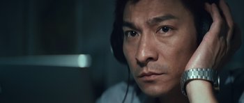 Movie still from “Infernal Affairs” (2002), directed by Alan Mak – A person wearing headphones and looking at the camera; Close Up shot, Low angle