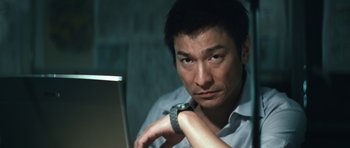 Movie still from “Infernal Affairs” (2002), directed by Alan Mak – A man sitting in front of a laptop computer; Close Up shot, Low angle