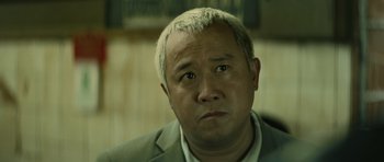 Movie still from “Infernal Affairs” (2002), directed by Alan Mak – A person wearing a suit and tie; Close Up shot, Low angle