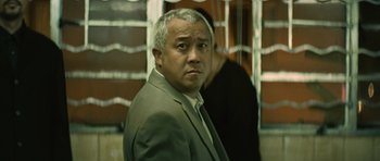 Movie still from “Infernal Affairs” (2002), directed by Alan Mak – A person wearing a suit and tie; Close Up shot, Low angle