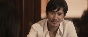 Movie still from “Infernal Affairs” (2002), directed by Alan Mak – A person wearing a white shirt; Close Up shot, Over the shoulder angle