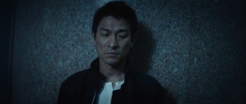 Movie still from “Infernal Affairs” (2002), directed by Alan Mak – A man in a black jacket is looking down; Close Up shot, Low angle