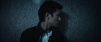 Movie still from “Infernal Affairs” (2002), directed by Alan Mak – A man with a black jacket is looking down; Close Up shot, Low angle