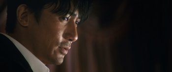 Movie still from “Infernal Affairs” (2002), directed by Alan Mak – A man's face in a dark room; Close Up shot, Low angle