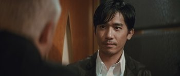 Movie still from “Infernal Affairs” (2002), directed by Alan Mak – A person wearing a suit and tie; Close Up shot, Over the shoulder angle