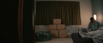 Movie still from “Infernal Affairs” (2002), directed by Alan Mak – A room filled with boxes and a couch in the corner; Wide shot, High angle