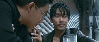 Movie still from “Infernal Affairs” (2002), directed by Alan Mak – Two asian men sitting next to each other; Close Up shot, Over the shoulder angle