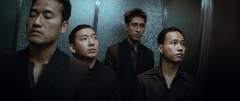 Movie still from “Infernal Affairs” (2002), directed by Alan Mak – A group of men in suits standing next to each other in an elevator; Medium shot, Low angle