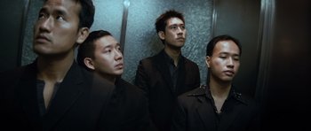 Movie still from “Infernal Affairs” (2002), directed by Alan Mak – A group of young men standing next to each other in an elevator; Medium shot, Low angle