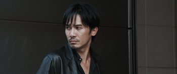 Movie still from “Infernal Affairs” (2002), directed by Alan Mak – A person wearing a black jacket; Close Up shot, Low angle