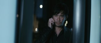 Movie still from “Infernal Affairs” (2002), directed by Alan Mak – A man is talking on a cell phone in the dark; Close Up shot, High angle