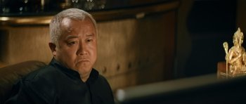 Movie still from “Infernal Affairs” (2002), directed by Alan Mak – An older asian man looking at a computer screen; Close Up shot, Low angle