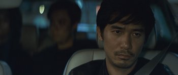 Movie still from “Infernal Affairs” (2002), directed by Alan Mak – A person sitting in a car; Close Up shot, Over the shoulder angle