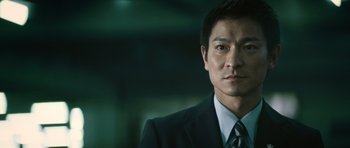 Movie still from “Infernal Affairs” (2002), directed by Alan Mak – A person wearing a suit and tie; Close Up shot, Low angle