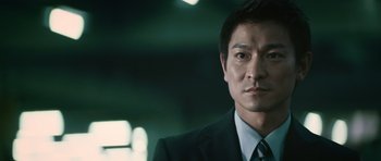 Movie still from “Infernal Affairs” (2002), directed by Alan Mak – A person wearing a suit and tie; Close Up shot, Low angle