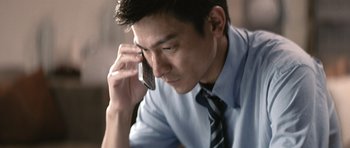 Movie still from “Infernal Affairs” (2002), directed by Alan Mak – A man in a dress shirt and tie talking on a cell phone; Close Up shot, High angle