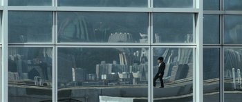 Movie still from “Infernal Affairs” (2002), directed by Alan Mak – A man in a black suit is standing in front of a window; Extreme Wide shot, Low angle