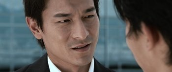 Movie still from “Infernal Affairs” (2002), directed by Alan Mak – A person wearing a suit and tie; Close Up shot, Over the shoulder angle