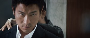 Movie still from “Infernal Affairs” (2002), directed by Alan Mak – A person wearing a suit and tie; Close Up shot, Low angle