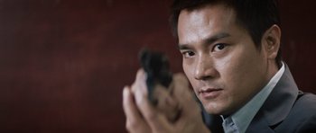 Movie still from “Infernal Affairs” (2002), directed by Alan Mak – A person holding a gun; Close Up shot, Low angle