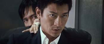 Movie still from “Infernal Affairs” (2002), directed by Alan Mak – A person wearing a suit and tie; Close Up shot, Low angle