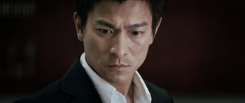 Movie still from “Infernal Affairs” (2002), directed by Alan Mak – A person wearing a suit and tie; Close Up shot, Low angle