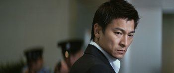 Movie still from “Infernal Affairs” (2002), directed by Alan Mak – A person wearing a suit and tie; Close Up shot, Low angle